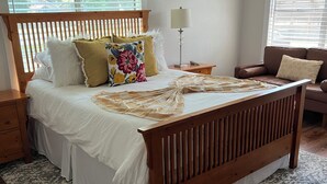 Une chambre à coucher avec un lit en bois, une table de chevet, une lampe et une fenêtre avec des stores.