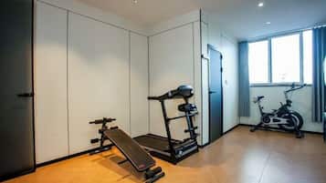 A room with a treadmill, stationary bike, and a bench.