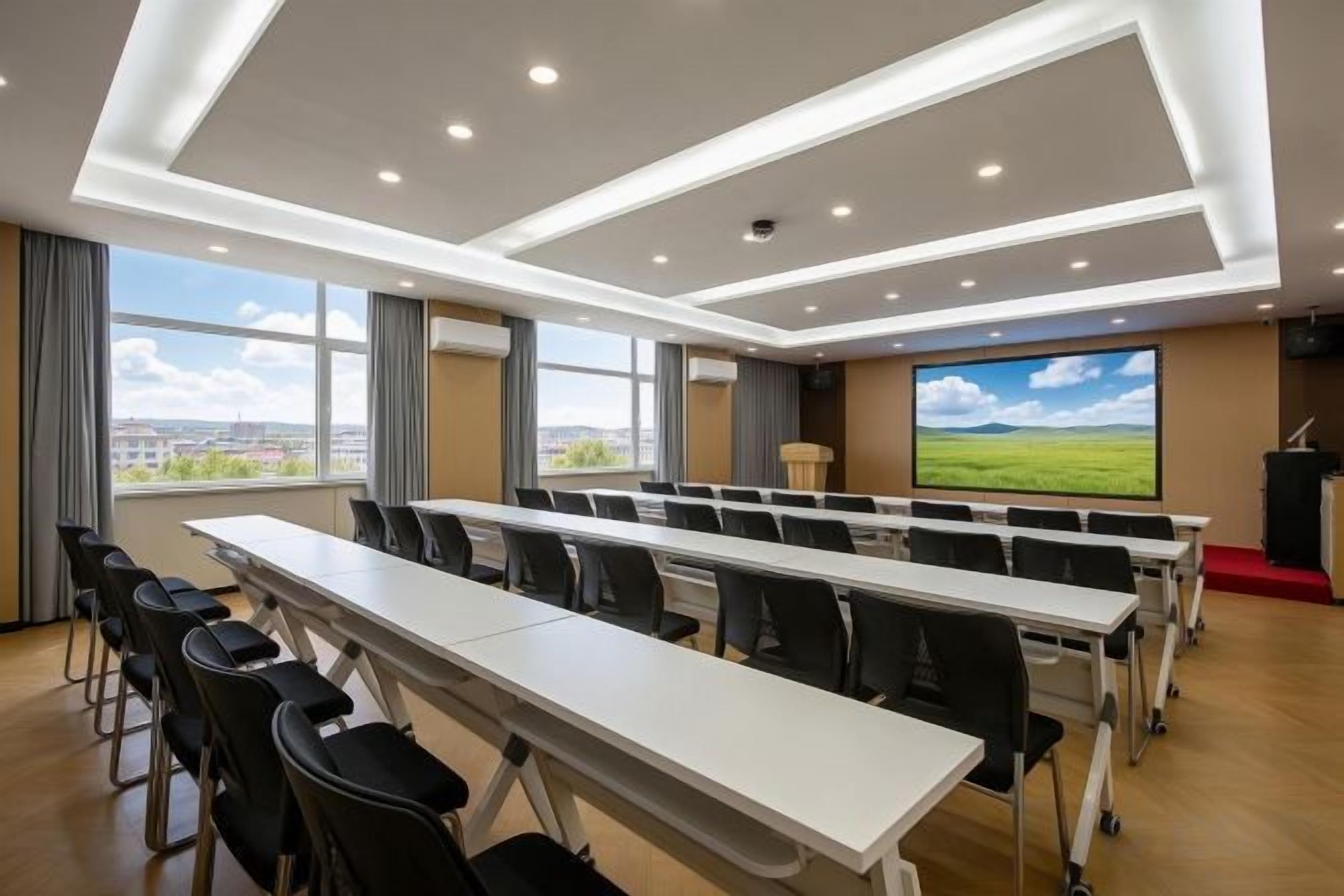 Un salón de conferencias con una larga mesa, sillas, una pantalla de proyector y vistas a la ciudad.