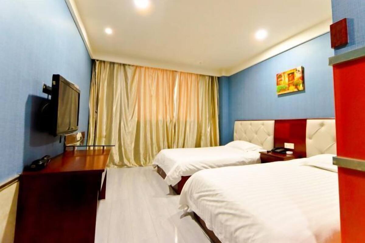 A hotel room with two beds, a TV, and a desk.
