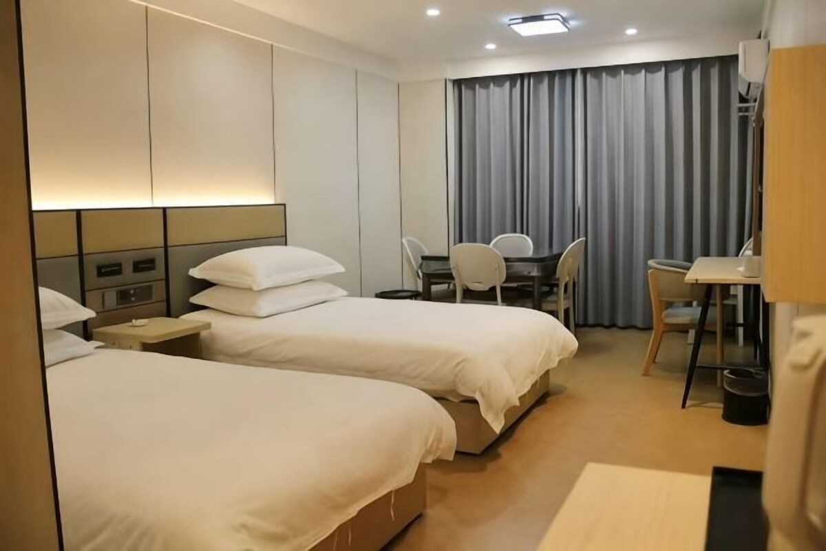 A hotel room with two beds, a desk, and a chair.