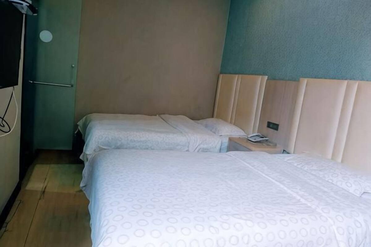 A room with two beds, a wooden floor, a green wall, and a door.