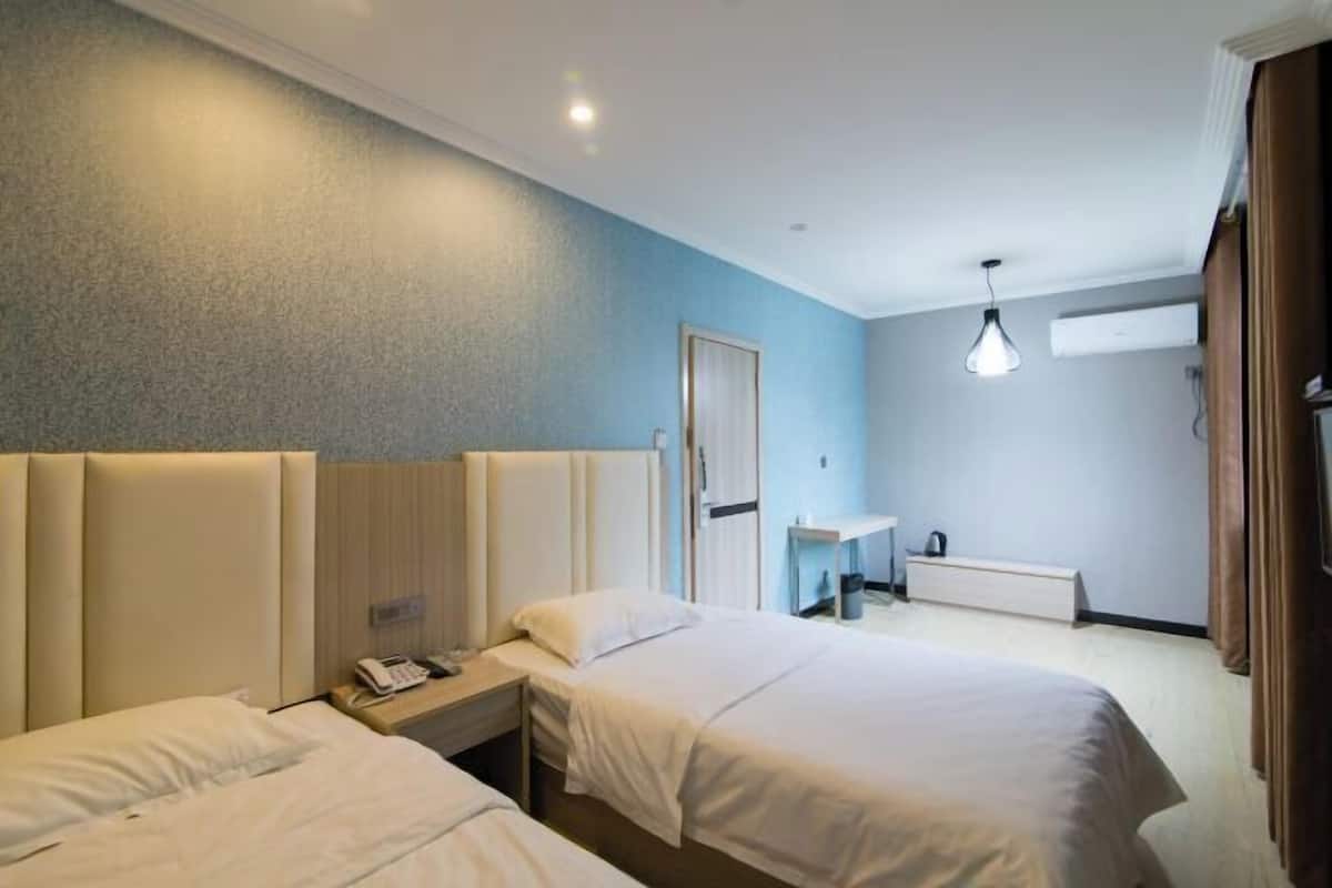 Ein Hotelzimmer mit zwei Betten, einem Nachttisch mit Telefon, einem kleinen Schreibtisch und einer Lampe.