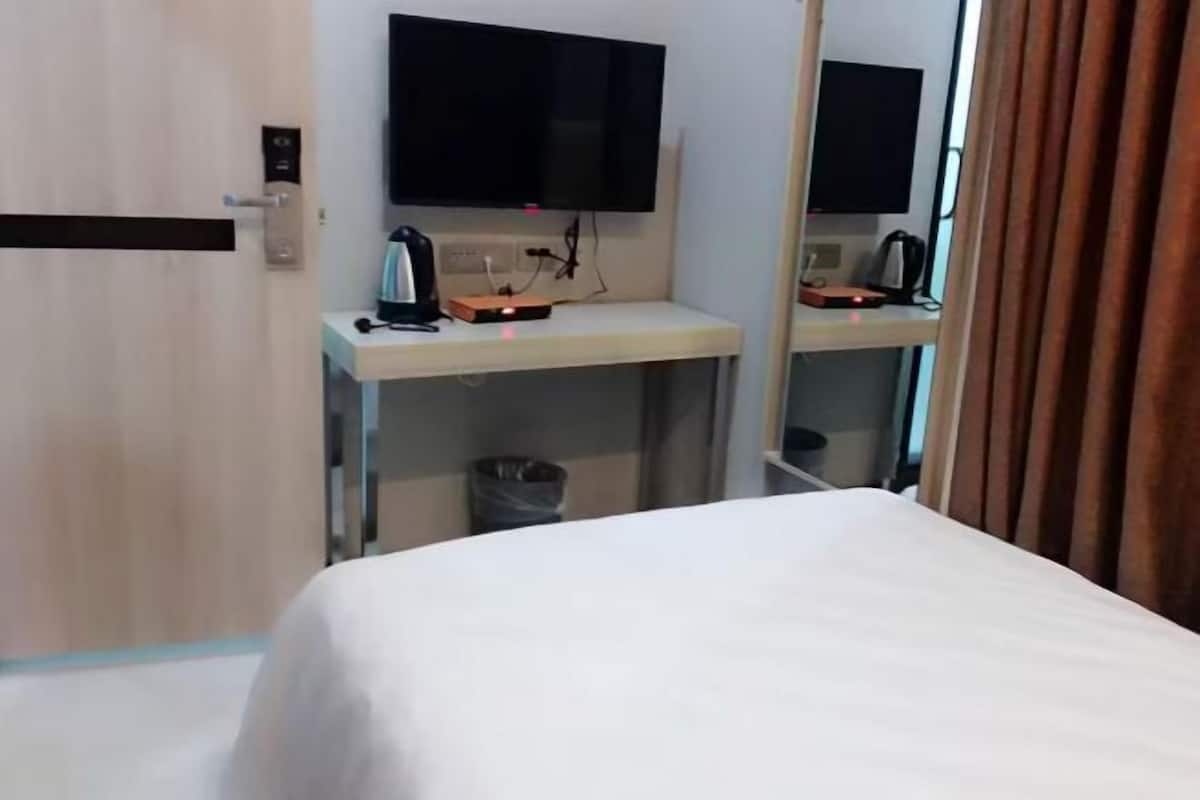 Ein Hotelzimmer mit einem Bett, einem Schreibtisch mit Flachbildfernseher, einer Kaffeemaschine und einem Mülleimer.