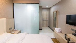 A hotel room with a bed, bedside table, TV, and a mirror. - Nanyang Yuyu Inn (Nanyang)