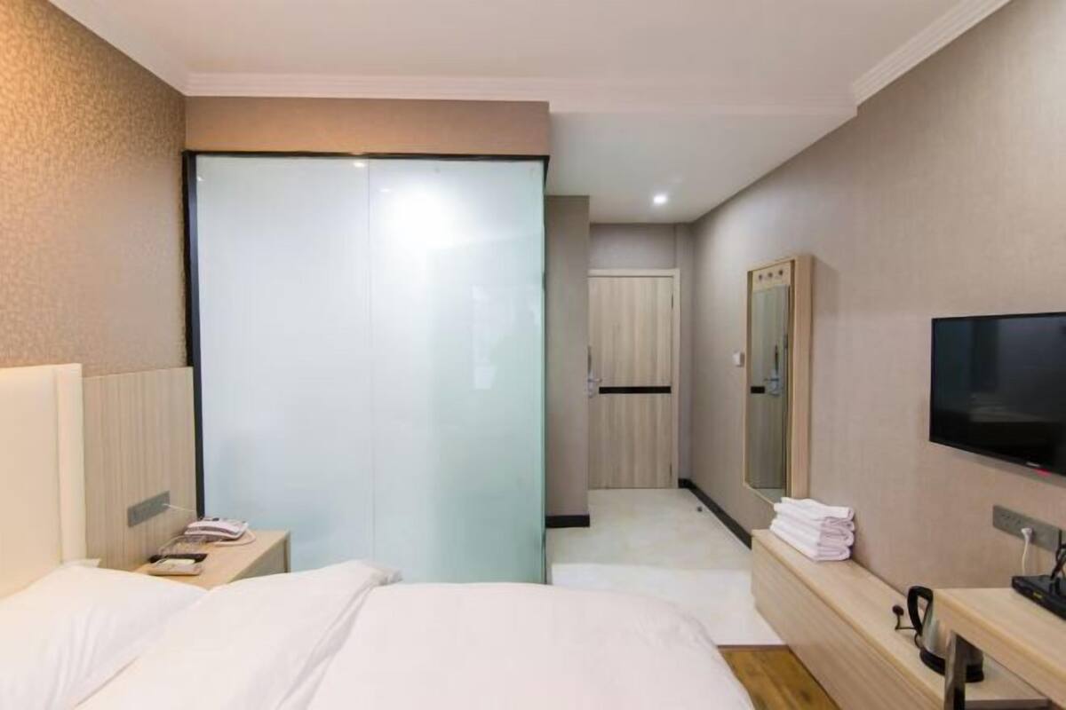 Ein Hotelzimmer mit Bett, Nachttisch, Fernseher und Spiegel.
