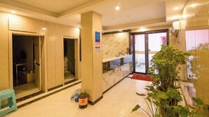 A hotel lobby with a reception desk, a glass door entrance, and a plant. - Nanyang Yuyu Inn (Nanyang)