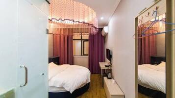 Habitación de hotel con dos camas, un escritorio, una silla, un espejo y una ventana con cortinas.