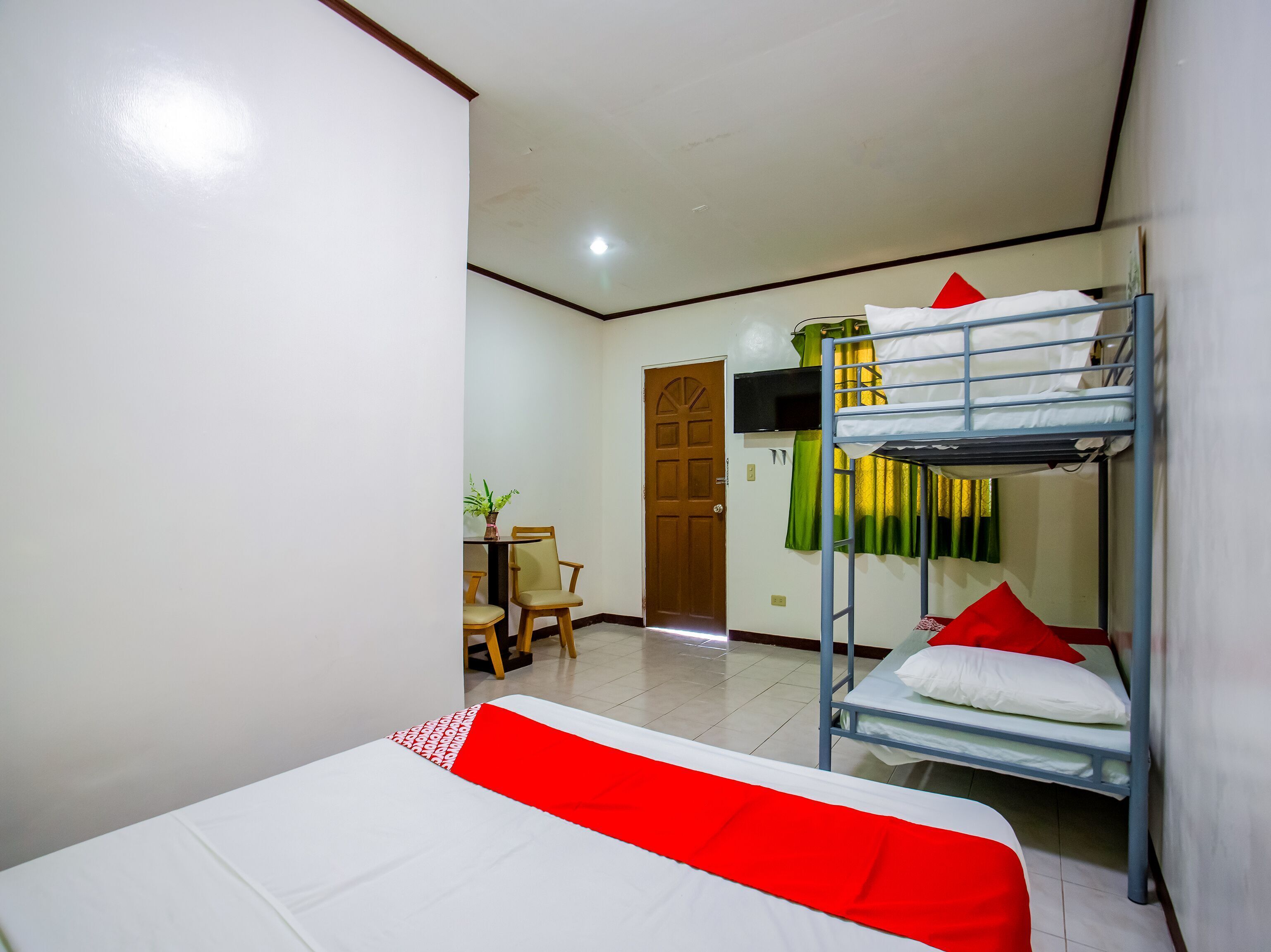 A room with bunk beds, a desk with a chair, and a door.