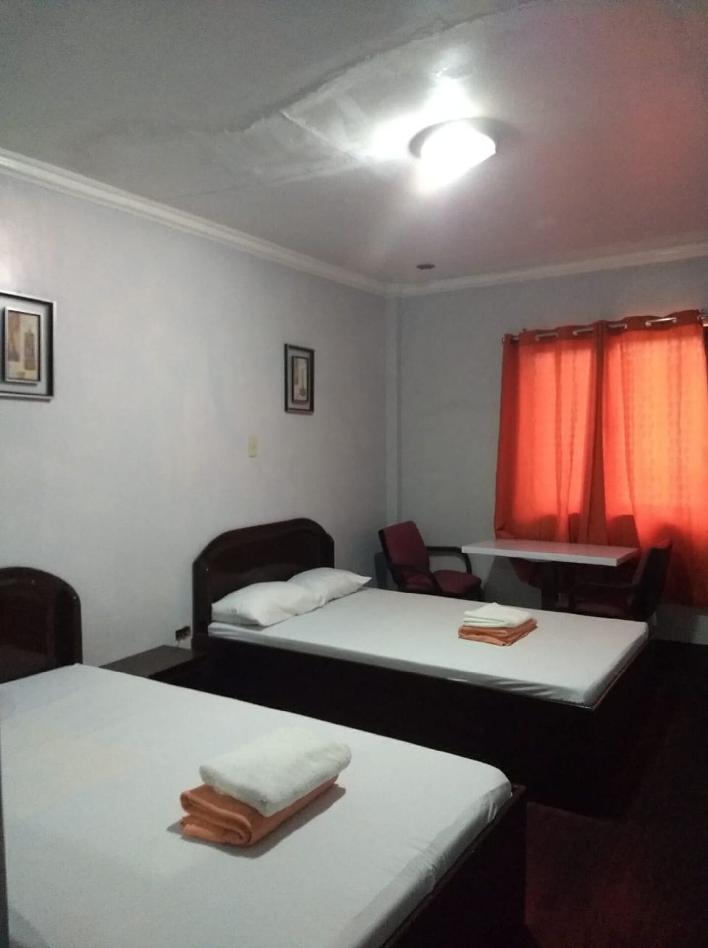 A room with two single beds, a desk, a chair, and a table.