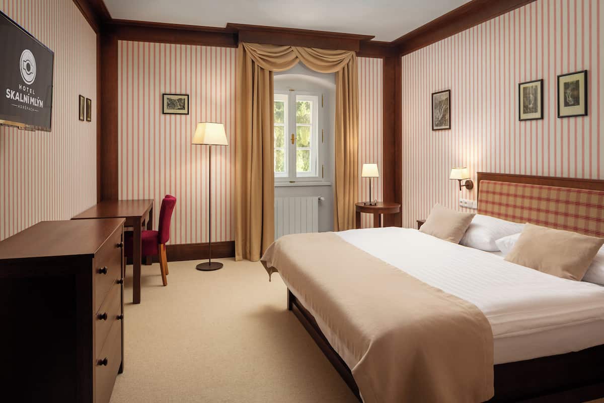 Una habitación de hotel con cama, escritorio, silla y puerta.