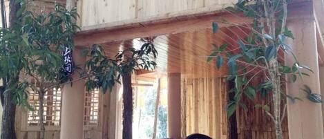Una struttura in legno con tavolo e sedie, immersa tra gli alberi.