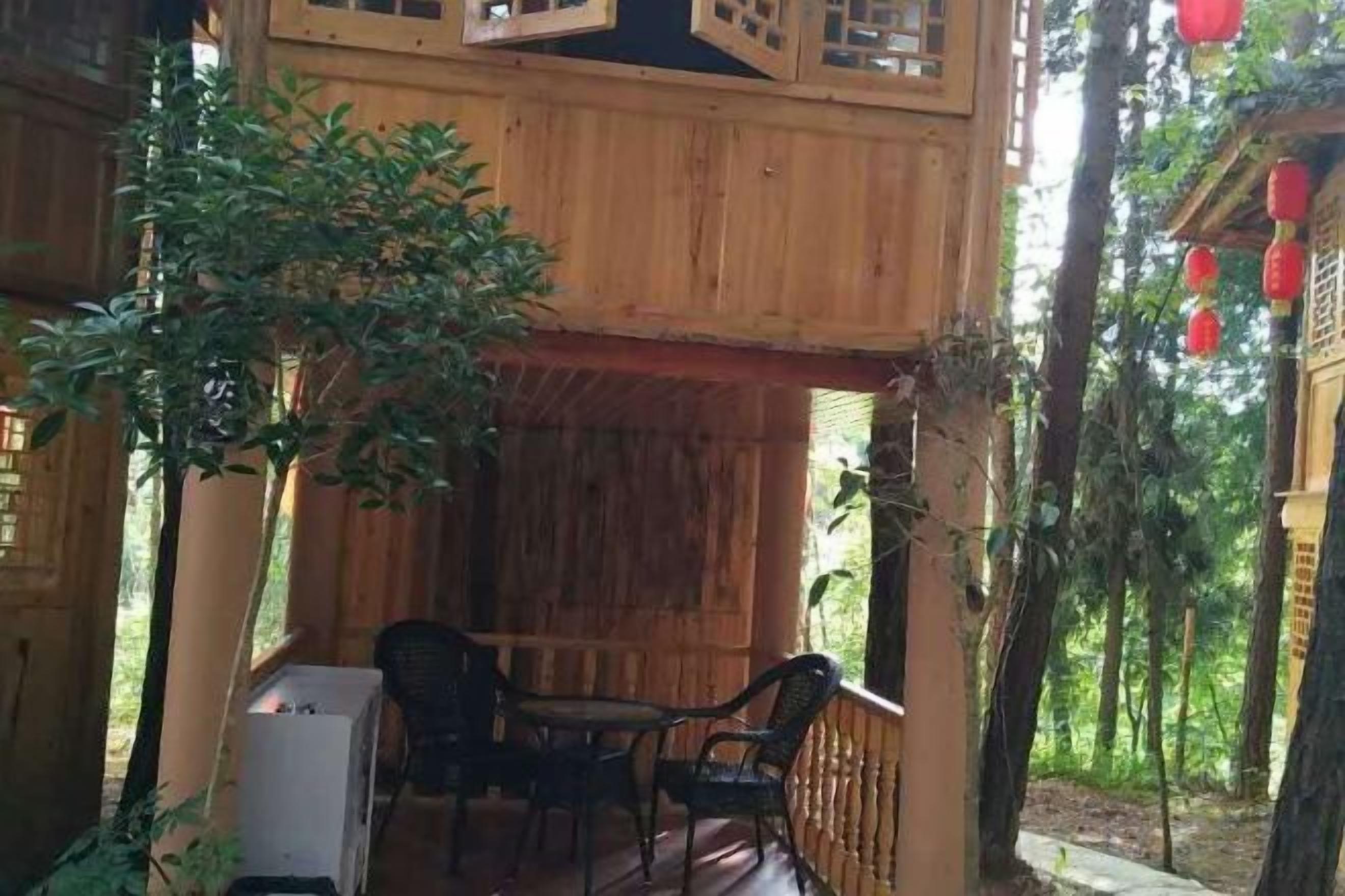 Una cabaña de madera con un porche cubierto, una mesa y sillas.