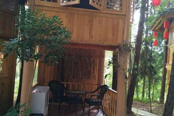 Une cabane en bois avec une véranda couverte, une table et des chaises.
