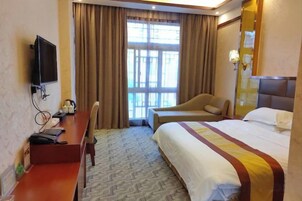A hotel room with a bed, a desk with a chair, a television, and a window with curtains.