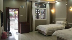 A hotel room with two beds, a wooden cabinet, a window with curtains, and a television. - Lichuan Chunhuiyuan Homestay (Lichuan)