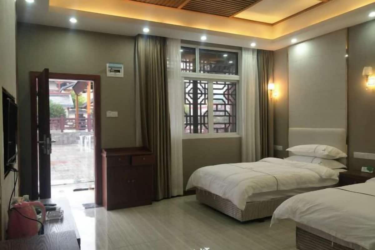 Habitación de hotel con dos camas, un armario de madera, una ventana con cortinas y un televisor.