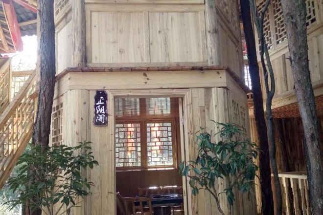 Un edificio de madera tradicional con un letrero, ventanas con celosías de madera y un banco en el exterior.