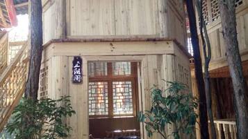 Un edificio de madera tradicional con un letrero, ventanas con celosías de madera y un banco en el exterior.