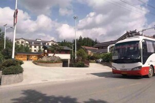 A bus at a bus stop with a building in the background.