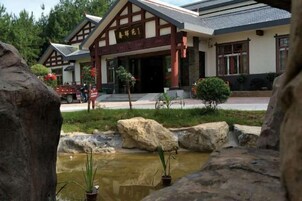 A traditional building with a wooden facade, a stone pathway, and a small water feature.
