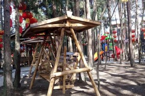 Een houten constructie met een plat dak, omgeven door bomen en rode lantaarns.