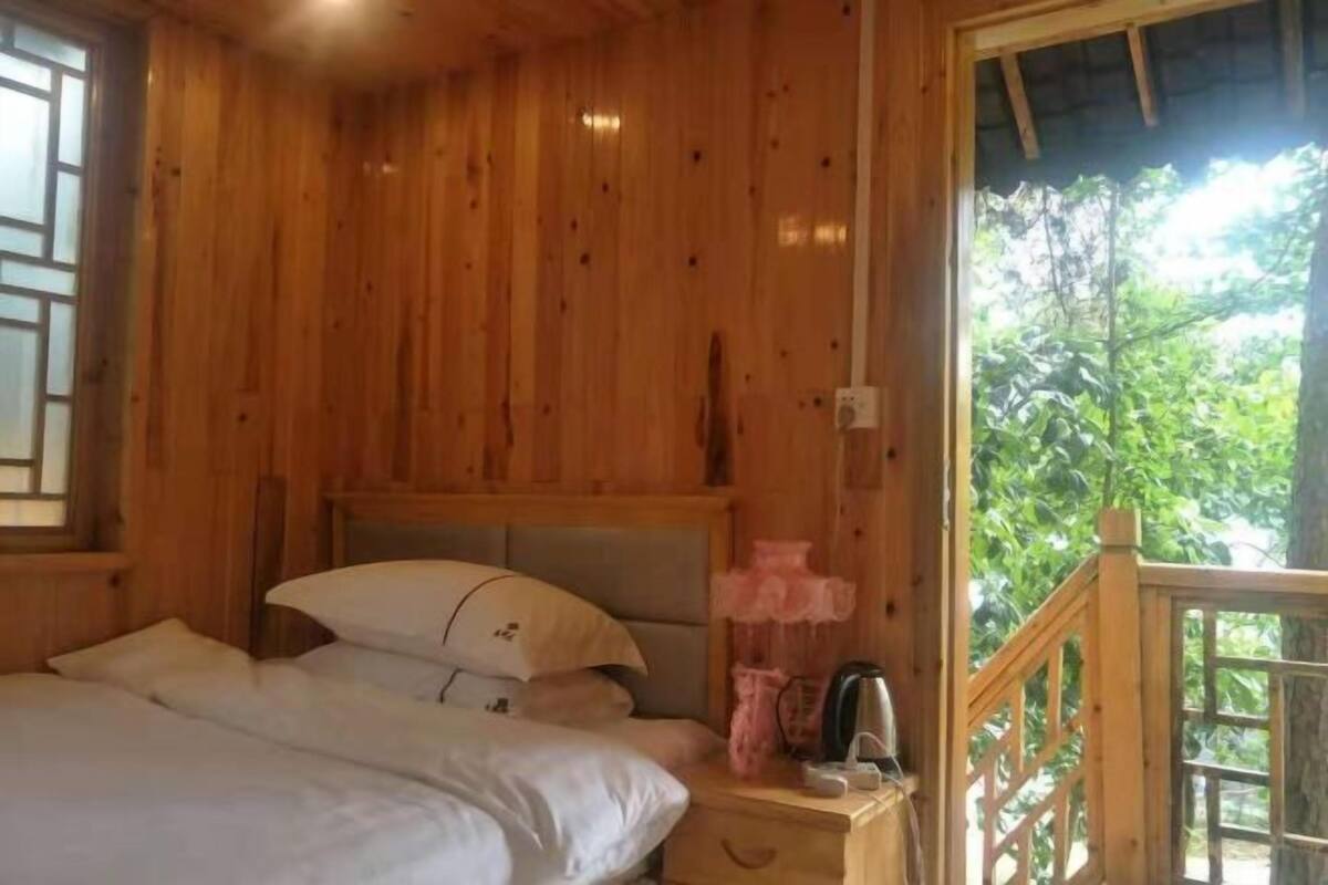 Una habitación de madera con una cama, una mesita de noche y un ventanal.