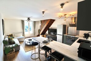 Une cuisine moderne dotée d’un îlot central, d’un coin repas avec un canapé et d’un escalier menant à un niveau supérieur.
