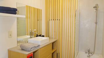 Un bagno con un lavandino bianco, uno specchio e una doccia.