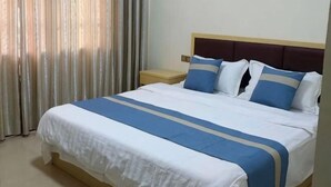 A neatly made bed with a blue and white bedspread, a wooden headboard, and a nightstand with a lamp. - Shizhu Mountain Forest Story Country Inn (Shizhu County)