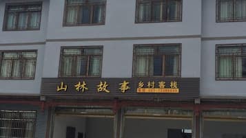 Un hotel con varios pisos, ventanas amplias y un cartel con información de contacto.
