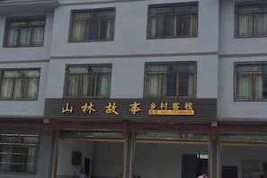 Un hotel con varios pisos, ventanas amplias y un cartel con información de contacto.