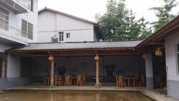 Un patio con piscina, mobiliario de madera y un edificio con tejado de baldosas.