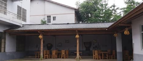 Ein Innenhof mit Pool, Holzmöbeln und einem Gebäude mit Ziegeldach.