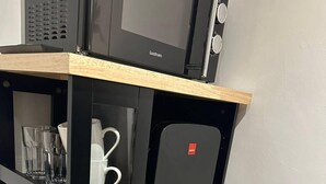 A compact kitchen unit with a microwave, a coffee maker, and a glass cabinet.