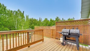 Eine Holzterrasse mit Grill und Holzzaun.