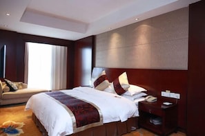 A hotel room with a large bed, a sofa, a nightstand with a phone, and a window with curtains. - Mingdu Hoki International Hotel (Changzhou)