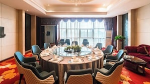 A conference room with a glass table surrounded by chairs, a chandelier, and large windows with curtains. - Mingdu Hoki International Hotel (Changzhou)