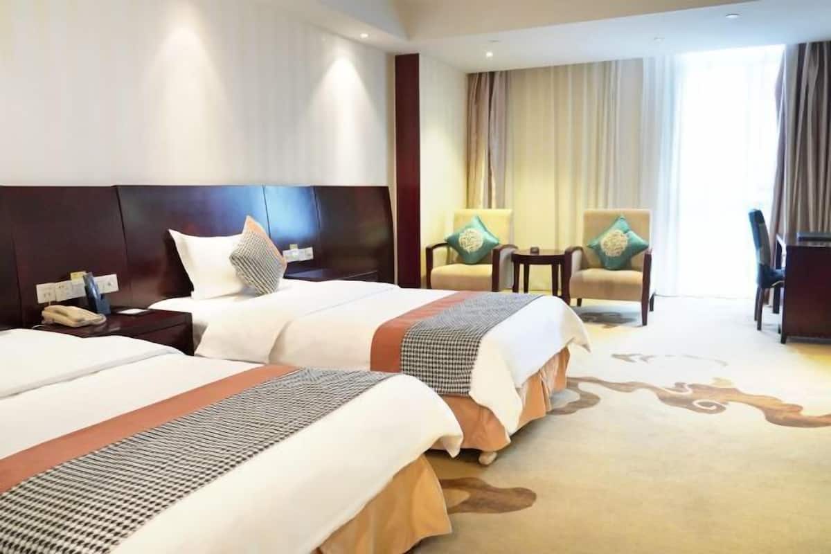A hotel room with two beds, a nightstand with a phone, a chair, and a small table.