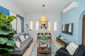 A modern living room with a grey sofa, a coffee table, and a TV mounted on the wall.