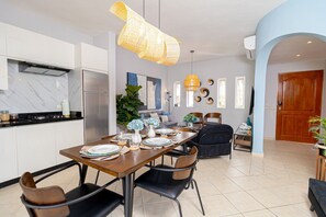 A modern kitchen with a dining area, featuring a large island, stainless steel appliances, and a unique woven light fixture.