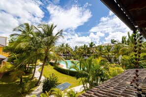 A resort with a swimming pool surrounded by palm trees and a clear blue sky. - Charming 1BR in Dominicus w Pool (Dominicus)