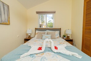 Une chambre d’hôtel avec un lit, deux tables de chevet avec des lampes, une fenêtre donnant sur un paysage agréable et une porte avec un volet en bois.