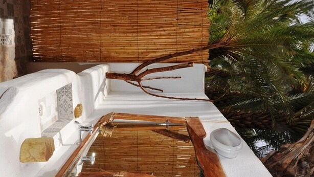 Ein Badezimmer mit einem weißen Waschbecken, einer Bambuswand und einer Holzzweig-Dekoration.