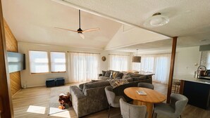 A spacious living area with a large sofa, a dining table, and a ceiling fan. -  Hatteras House  (Hatteras)
