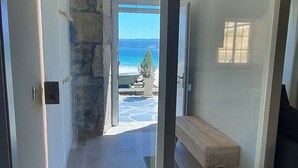Un intérieur moderne avec un mur d’accent en pierre, un banc et une vue sur la mer.