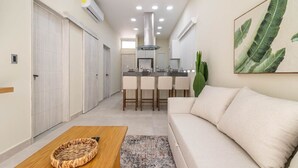 A compact living space with a kitchenette, a sofa, a coffee table, and a dining area with bar stools.