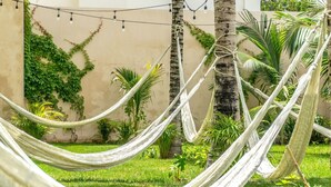 A hammock set up in a lush garden with palm trees and greenery.