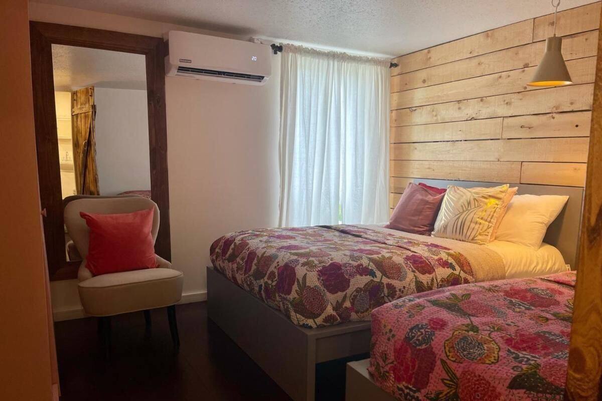 A room with two beds, a chair, and a wooden wall.