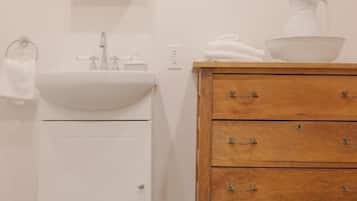 Un baño con un lavamanos blanco, un mueble de madera con cajones y un espejo sobre el lavamanos.